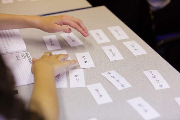 Student Using Algebraic Expressions On Pieces Of Paper